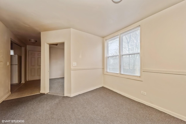 empty room with baseboards and dark carpet