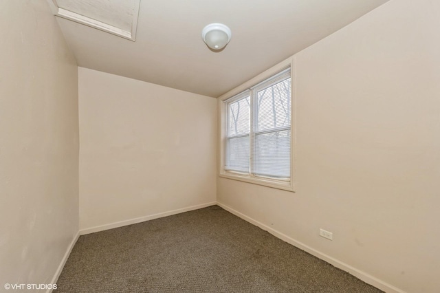 empty room featuring attic access, baseboards, dark colored carpet, and lofted ceiling