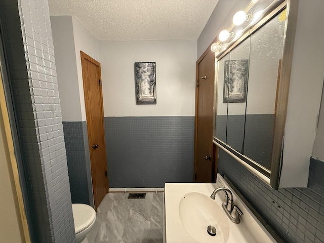 203 S Whitehead St, Tolono, IL 61880 - bathroom featuring vanity, a textured ceiling, marble finish floors, and a wainscoted wall