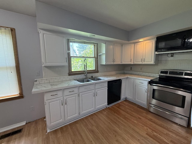 203 S Whitehead St, Tolono, IL 61880 - kitchen featuring black appliances, light countertops, light wood finished floors, and white cabinets