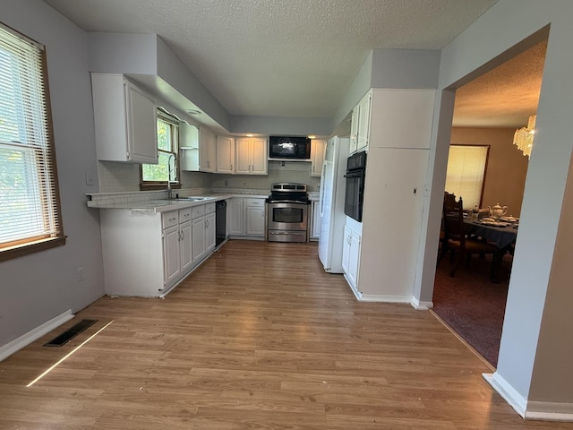 203 S Whitehead St, Tolono, IL 61880 - kitchen with black appliances, light countertops, light wood-style floors, white cabinets, and a textured ceiling