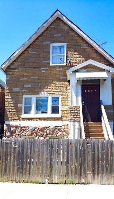 view of front facade featuring stone siding and a fenced front yard