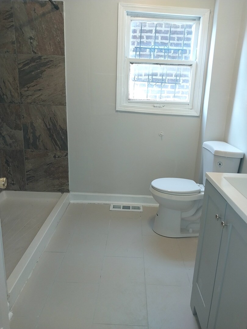 bathroom with toilet, a stall shower, baseboards, and visible vents