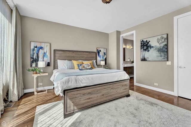 bedroom with wood finished floors, baseboards, and connected bathroom