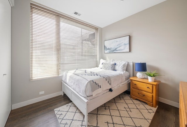 bedroom with wood finished floors, baseboards, and visible vents