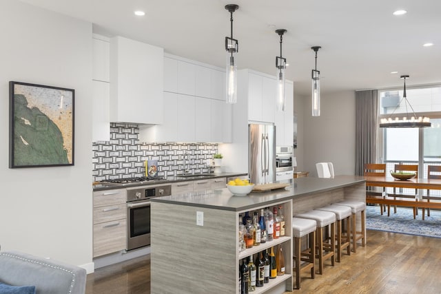 kitchen featuring a kitchen island, a breakfast bar, appliances with stainless steel finishes, dark countertops, and decorative backsplash