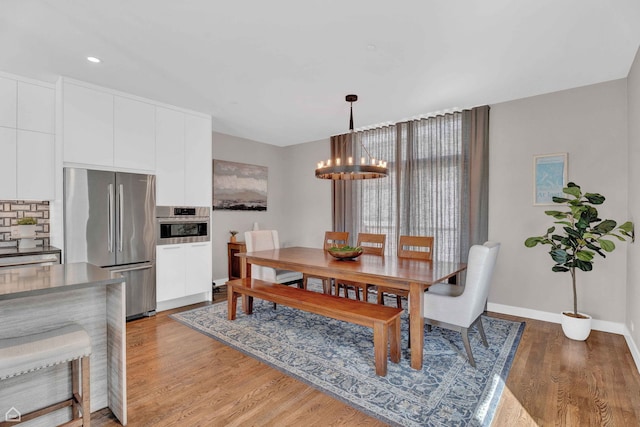 dining space with light wood-style flooring, recessed lighting, an inviting chandelier, and baseboards