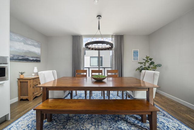 dining room with baseboards, an inviting chandelier, and wood finished floors