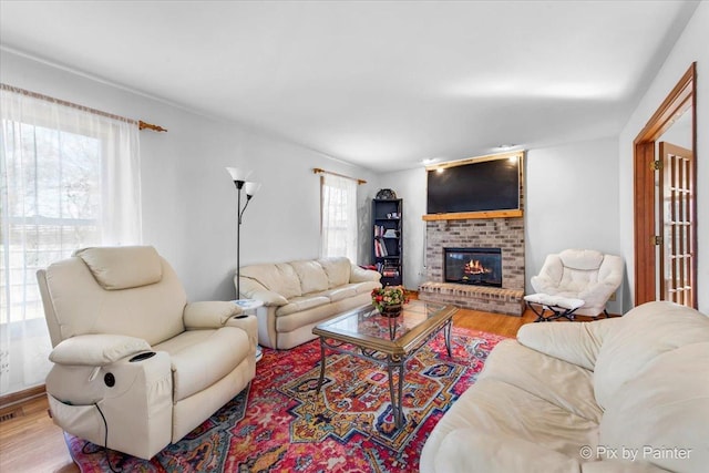 living room featuring a brick fireplace and wood finished floors