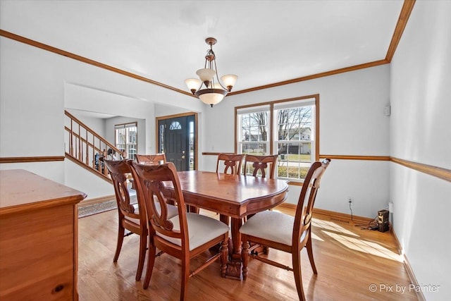 dining area featuring light wood-style flooring, baseboards, stairs, ornamental molding, and an inviting chandelier
