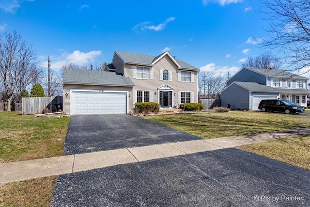 colonial home featuring an attached garage, aphalt driveway, fence, and a front yard