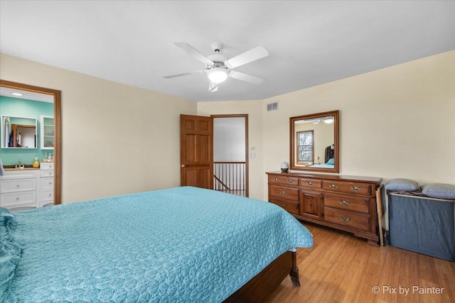 bedroom with light wood-type flooring, a sink, ceiling fan, and visible vents