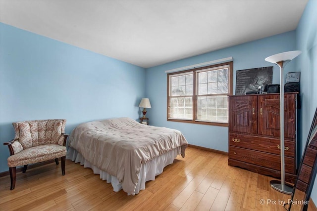 bedroom with light wood finished floors and baseboards