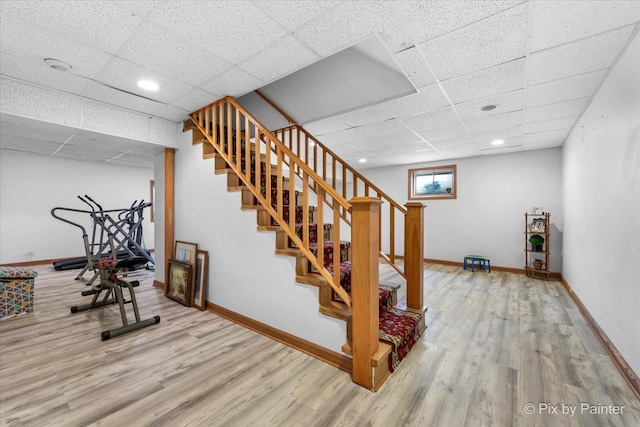 exercise area with baseboards, wood finished floors, and a paneled ceiling