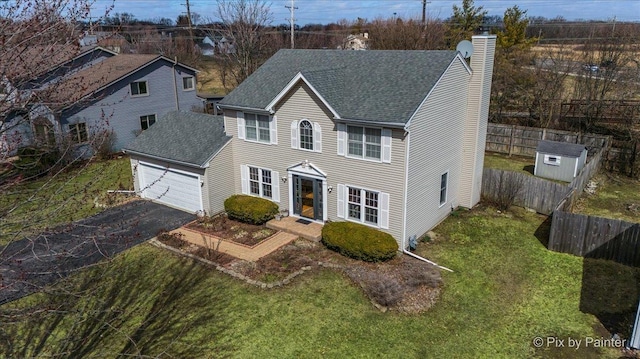 view of front of property with fence, roof with shingles, an attached garage, and aphalt driveway