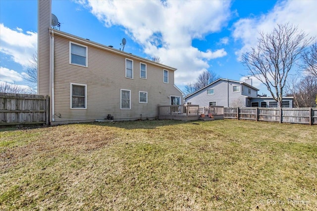 back of house with a fenced backyard, a wooden deck, and a yard
