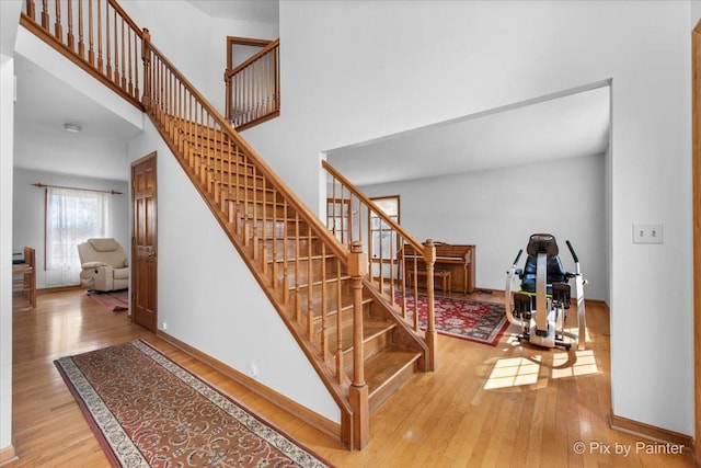 stairs with baseboards, wood finished floors, and a towering ceiling