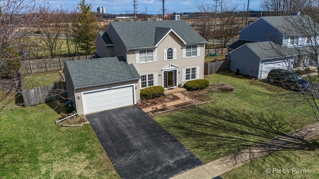 colonial home with aphalt driveway, a front yard, a garage, and roof with shingles