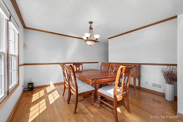 dining space with a chandelier, light wood-type flooring, baseboards, visible vents, and ornamental molding