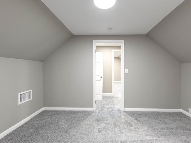 additional living space with baseboards, visible vents, lofted ceiling, and carpet