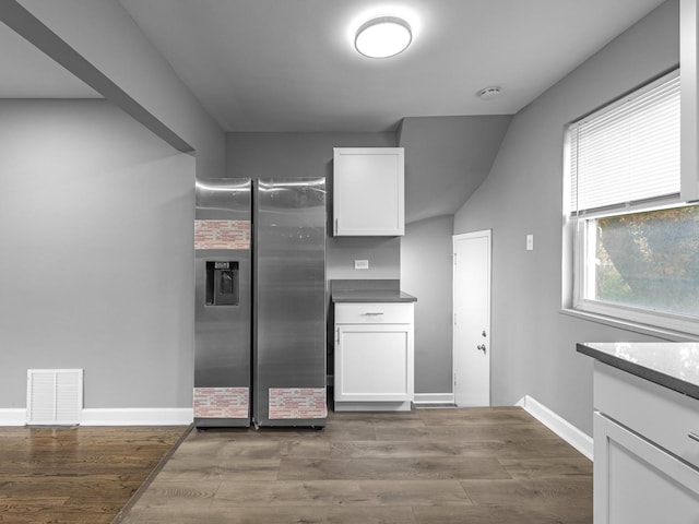 kitchen with dark wood-style flooring, white cabinets, visible vents, and stainless steel refrigerator with ice dispenser