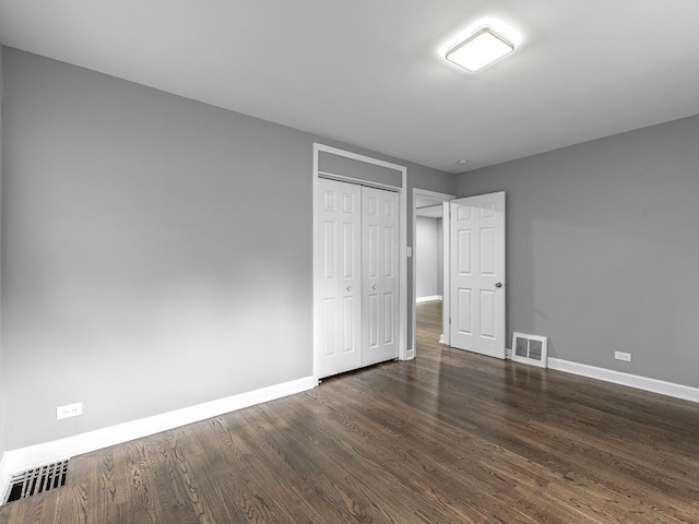 unfurnished bedroom featuring baseboards, visible vents, a closet, and dark wood-style flooring