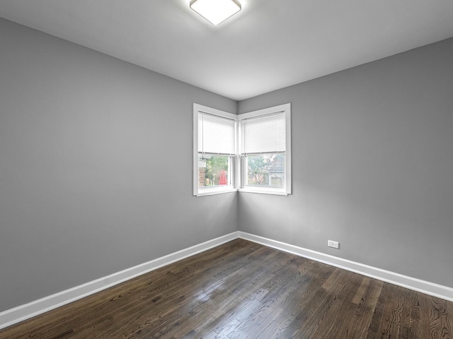 spare room with dark wood finished floors and baseboards