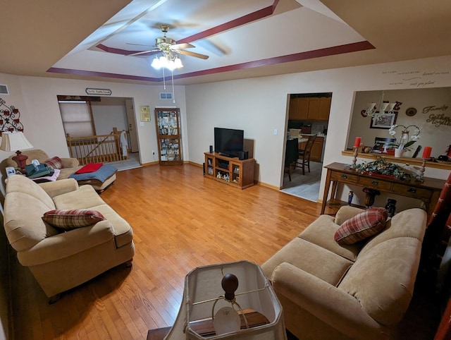 living area featuring baseboards, wood finished floors, ceiling fan, and a raised ceiling
