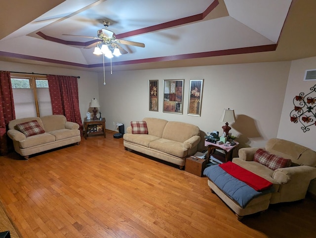 living area featuring light wood-type flooring, visible vents, ceiling fan, and a raised ceiling