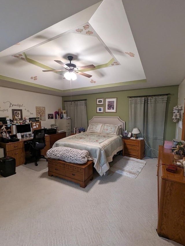bedroom featuring light colored carpet, a ceiling fan, and a raised ceiling