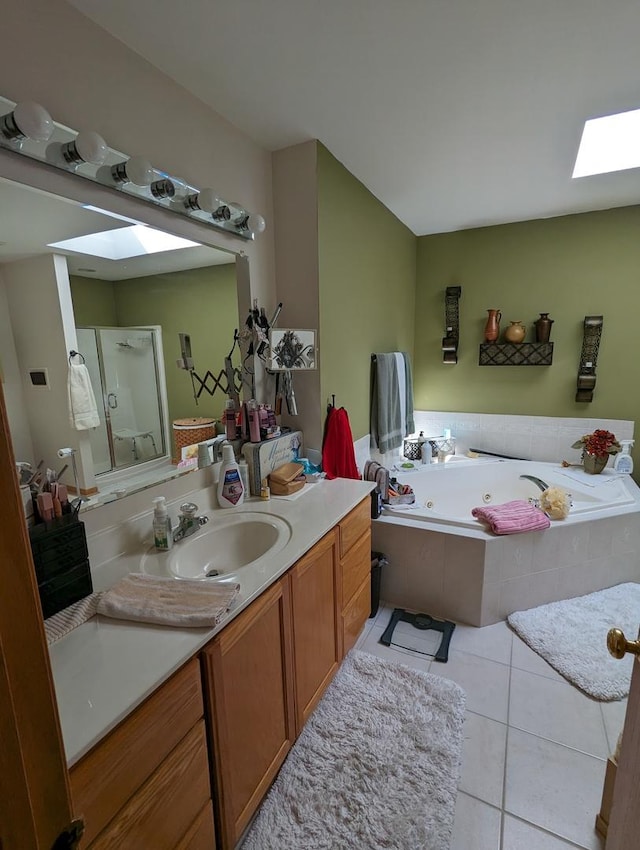 bathroom with vanity, a tub with jets, tile patterned floors, a skylight, and a stall shower