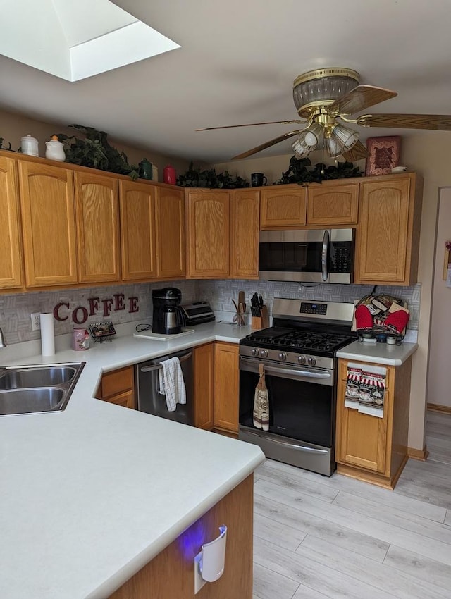 kitchen featuring light countertops, stainless steel appliances, decorative backsplash, a sink, and ceiling fan