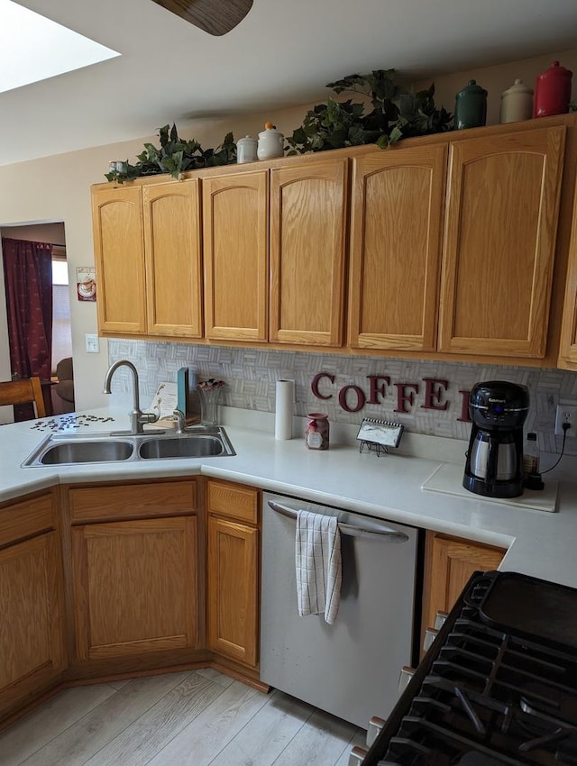 kitchen with decorative backsplash, light countertops, light wood finished floors, dishwasher, and a sink