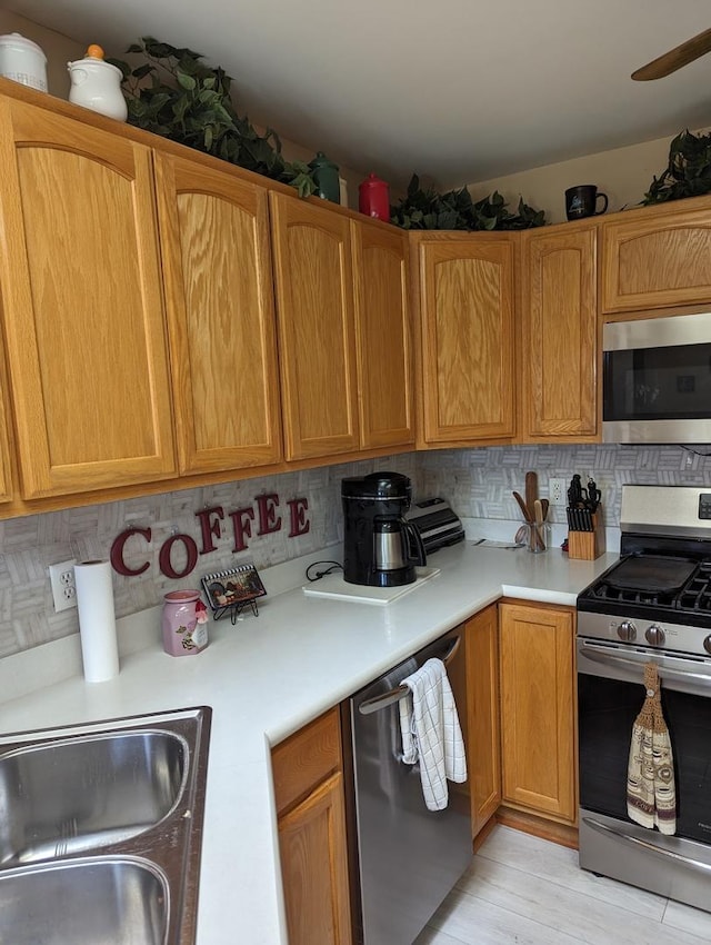 kitchen featuring backsplash, light countertops, a sink, and stainless steel appliances