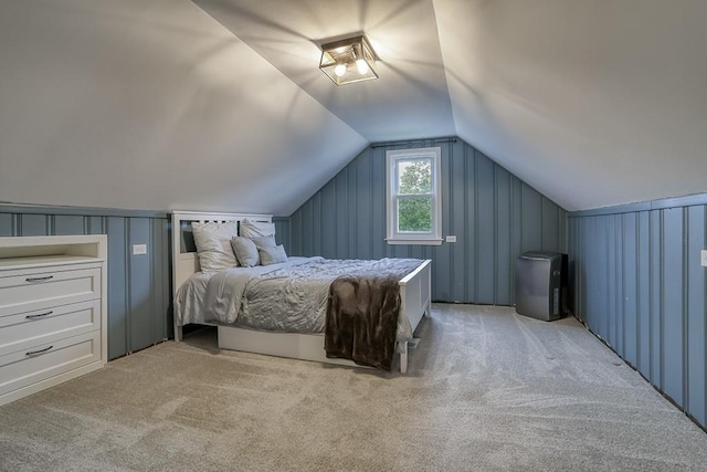 bedroom featuring vaulted ceiling, carpet, and a decorative wall