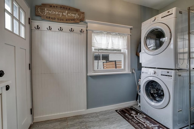 washroom featuring stacked washer and clothes dryer, baseboards, and wood finished floors