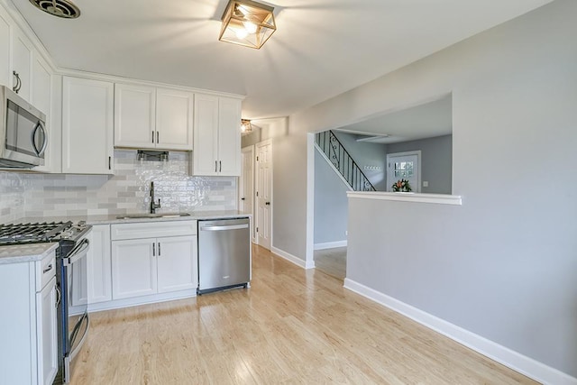 kitchen featuring stainless steel appliances, a sink, light countertops, tasteful backsplash, and white cabinets