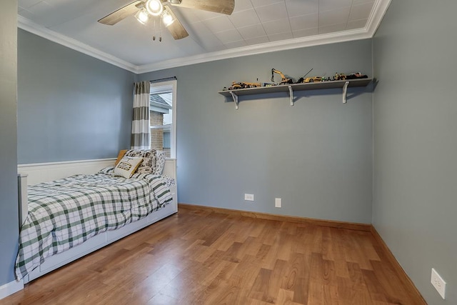 bedroom with wood finished floors, crown molding, a ceiling fan, and baseboards