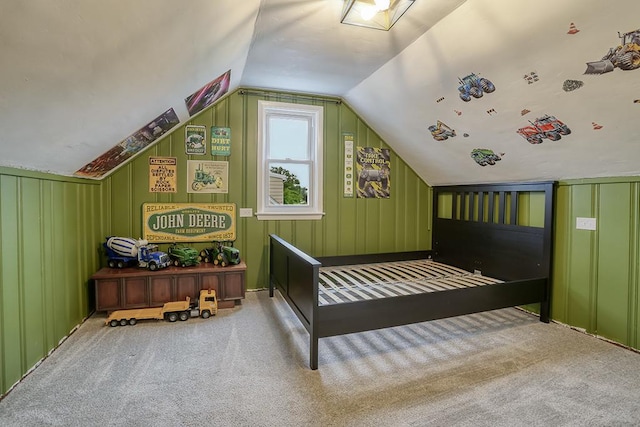 carpeted bedroom featuring vaulted ceiling and a decorative wall