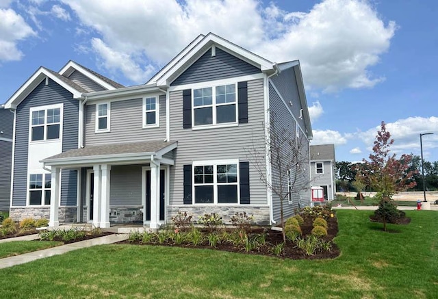 view of front of property with stone siding, covered porch, and a front lawn