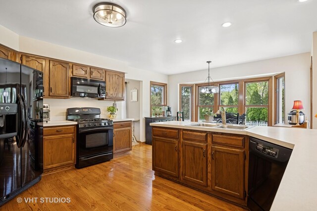 4230 Forest Glen Dr, Hoffman Estates, IL 60192 - kitchen featuring black appliances, light countertops, light wood-style floors, a sink, and hanging light fixtures