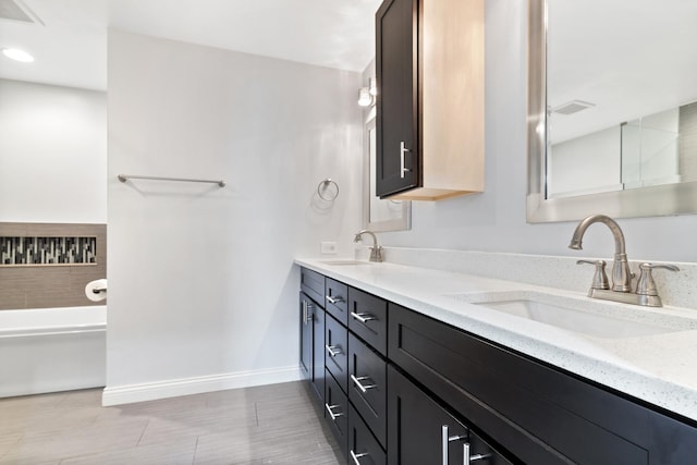 full bath featuring double vanity, visible vents, baseboards, and a sink