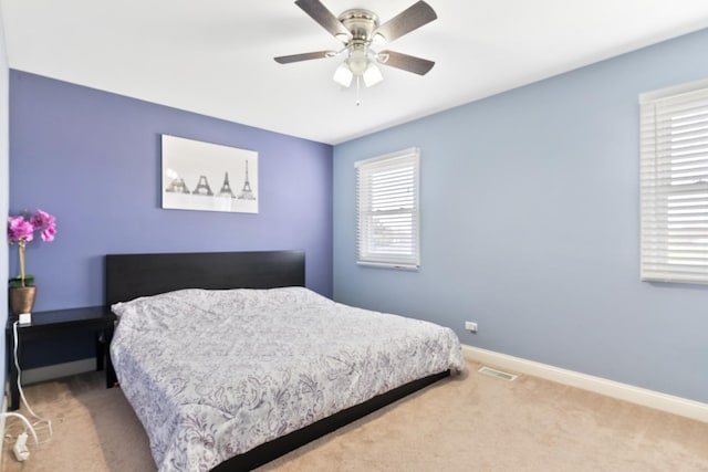 carpeted bedroom featuring visible vents, baseboards, and ceiling fan