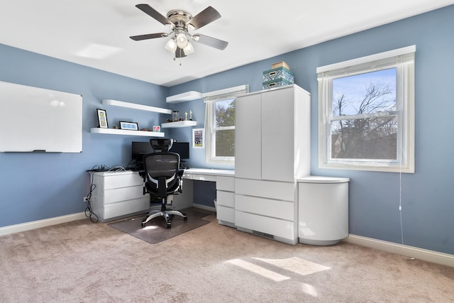 office area with baseboards, built in desk, an AC wall unit, a ceiling fan, and light colored carpet