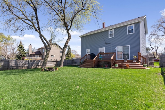 back of property with a fenced backyard, a wooden deck, and a lawn