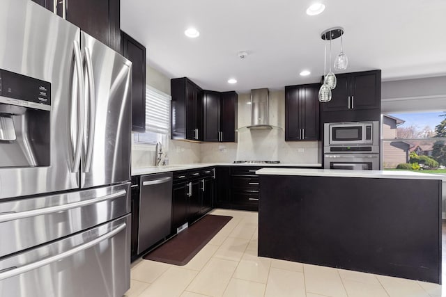 kitchen with wall chimney range hood, light countertops, backsplash, decorative light fixtures, and stainless steel appliances