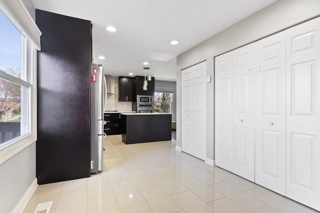 kitchen with light tile patterned floors, dark cabinets, recessed lighting, appliances with stainless steel finishes, and light countertops