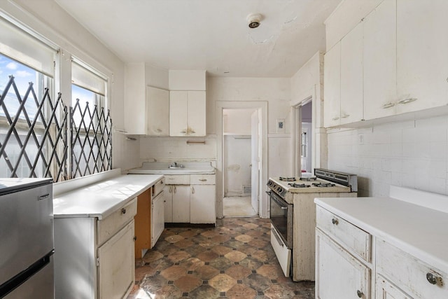 9241 S Blackstone Ave, Chicago, IL 60619 - kitchen with light countertops, freestanding refrigerator, white cabinetry, tasteful backsplash, and white range with gas cooktop
