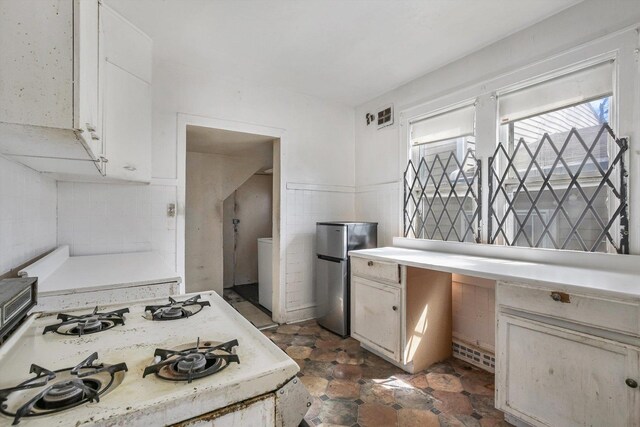 9241 S Blackstone Ave, Chicago, IL 60619 - kitchen featuring light countertops, freestanding refrigerator, white cabinetry, stone finish floor, and visible vents