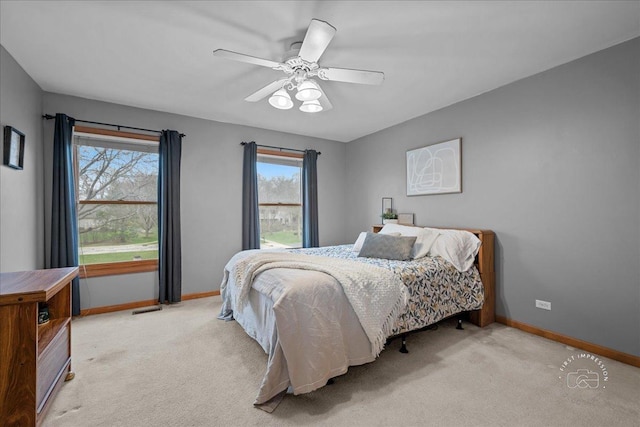 bedroom with light carpet, ceiling fan, and baseboards